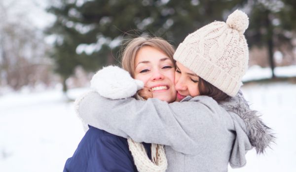 Mutter und Kind umarmen sich im Schnee