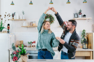 Young couple husband and wife happy preparing for New Year and Christmas celebration, family having fun dancing in the kitchen