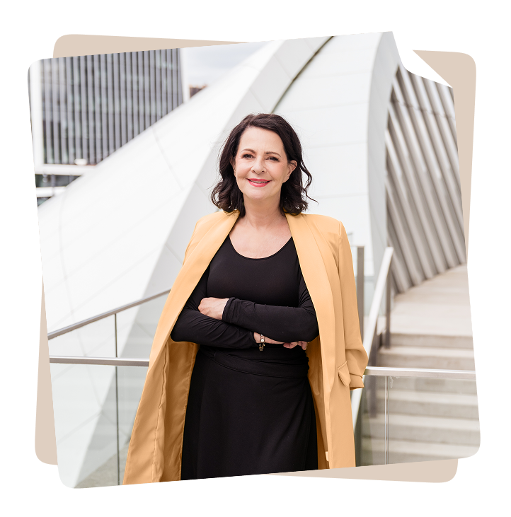 Stefanie Stahl steht lächelnd vor moderner Architektur – Symbolbild für Selbstvertrauen und Beziehungskompetenz