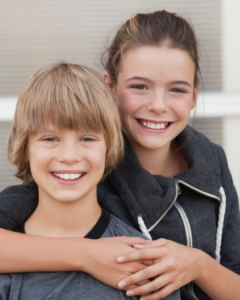 Zwei Geschwister, die sich umarmen und lächeln