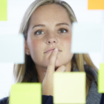 Nachdenkliche Frau blickt auf Haftnotizen und trifft eine Entscheidung – Symbolbild für Entscheidungen treffen, Entscheidungsfindung und Abwägen von Optionen im Alltag.