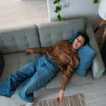 Frau liegt erschöpft auf dem Sofa – Symbolbild für Antriebslosigkeit, Müdigkeit und fehlende Motivation im Alltag.