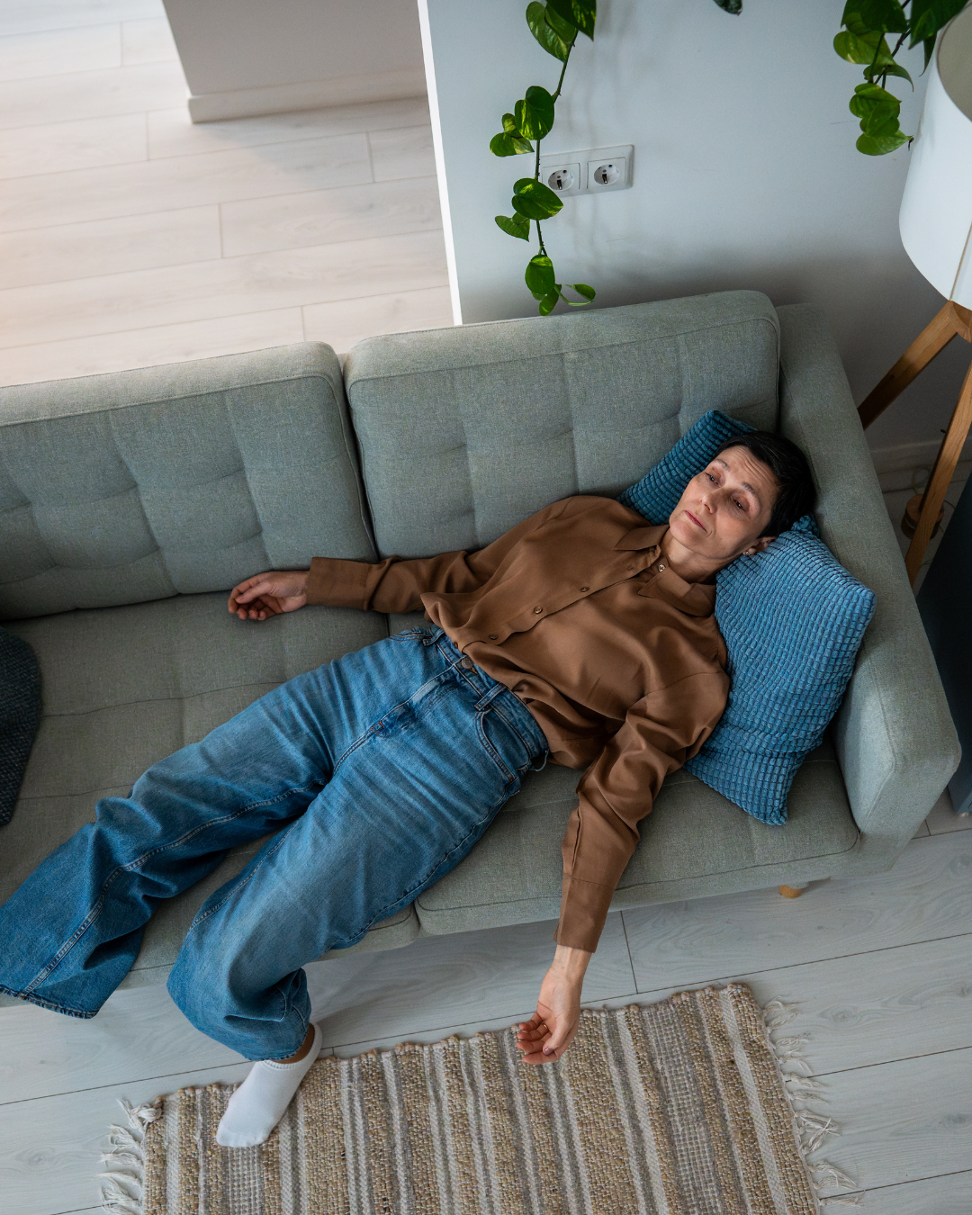 Frau liegt erschöpft auf dem Sofa – Symbolbild für Antriebslosigkeit, Müdigkeit und fehlende Motivation im Alltag.